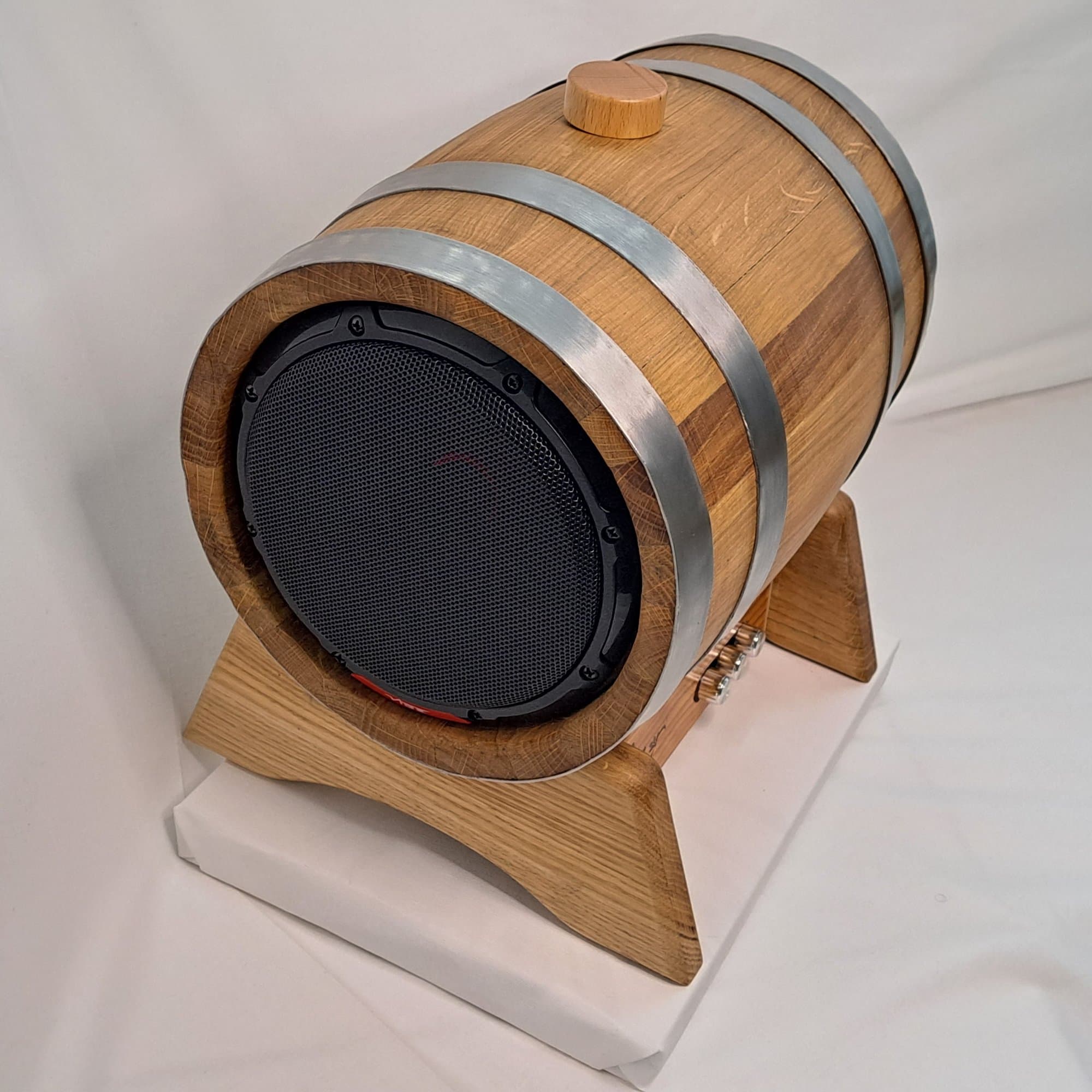 The oak barrel speaker from the front, showing the driver set into the end