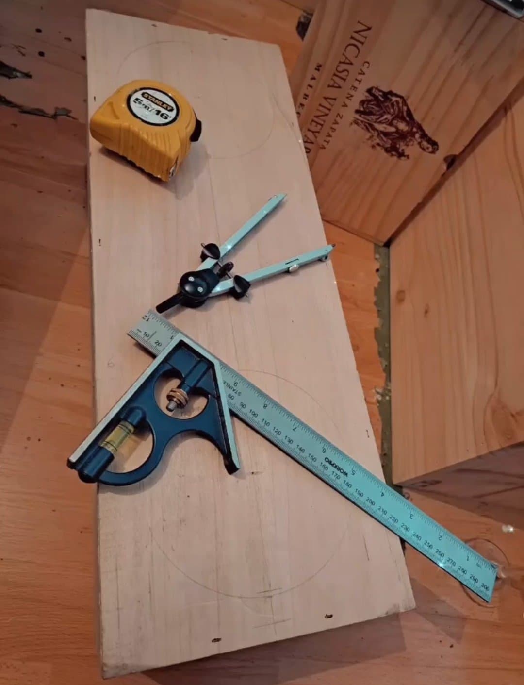 Tape measure, compass and combination square laid out on a pine board, marking up a new piece